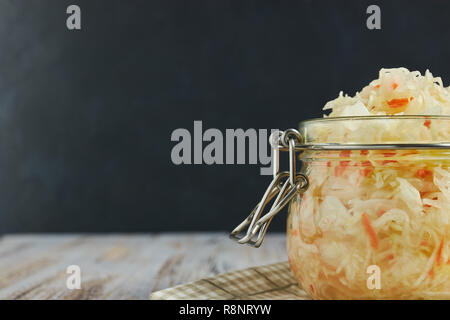 one jar of sauerkraut and carrots in its own juice with spices on a light, white wooden table, a vertical kind of cabbage in a jar. traditional home-m Stock Photo