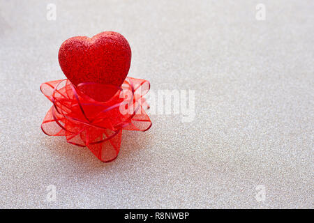 The red heart shapes on red bow on  silver glitter paper background  in love concept for valentines day. Copy space Stock Photo