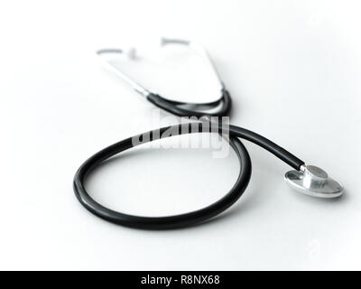 A doctors black flexible rubber and steel metal heart pulse stethoscope laying isolated on a white table top. Stock Photo