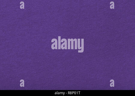 Dark purple matte background of suede fabric, closeup. Velvet texture of seamless violet woolen felt. Stock Photo