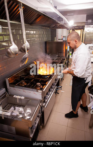 Chef cooking and doing flambe on food in restaurant kitchen , Great cook at work Stock Photo