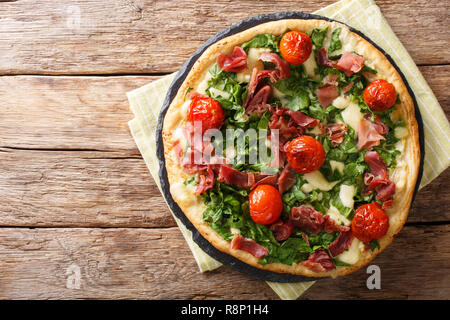 Freshly cooked hot pizza with spinach, tomatoes, prosciutto and cheese close-up on the table. horizontal top view from above Stock Photo