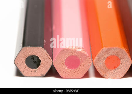 Macro of black pink orange color pencils, all lined up, isolated on white paper. Stock Photo