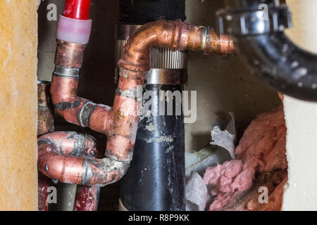 Close up detail of repaired plumbing pipes, drain and insulation inside residential wall. Stock Photo