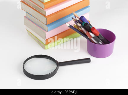 magnifying glass, pencils and stack of books on white background Stock Photo