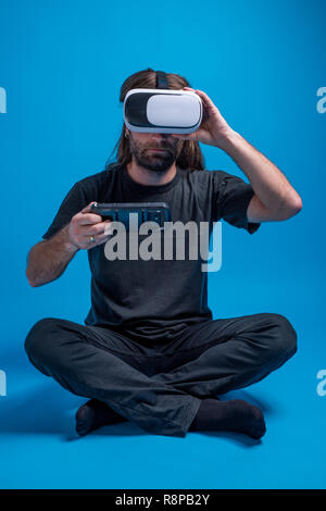 Male portrait wearing VR gear laying on the ground preparing the setup. Cyber gadget for casual experience Stock Photo