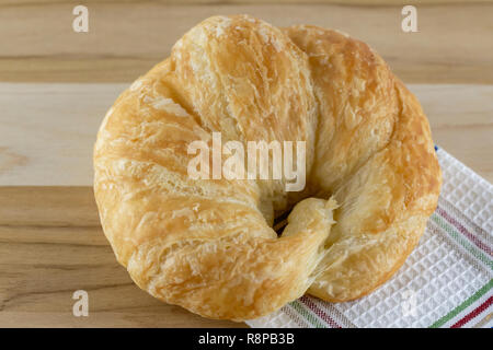 Single croissant on wooden board with cloth.  Top macro view. Stock Photo