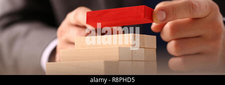 Male hand holds red wood block of stair Stock Photo