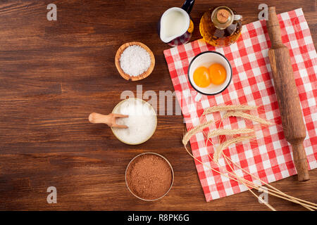 Flat lay or overhead view of baking tools and ingredients on wooden background. Stock Photo