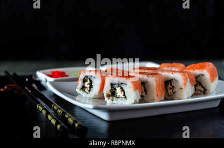 Philadelphia Sushi Roll made of Fresh Salmon, Avocado and Cream Cheese with black rice with cuttlefish ink inside. Traditional Japanese cuisine. Asian Stock Photo
