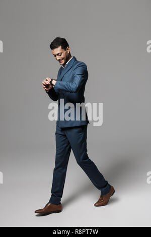 Full length image of businesslike arabic guy 30s in formal suit strolling  isolated over gray background Stock Photo - Alamy