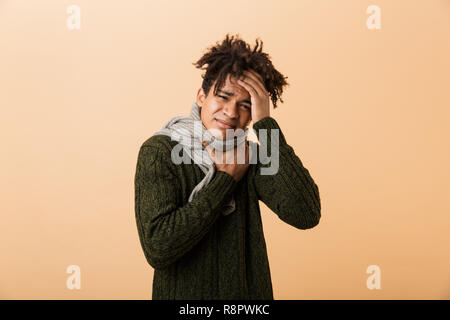 Portrait of a young african man dressed in autumn clothes isolated over beige background, suffering from a sore throat Stock Photo