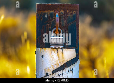 Padlock on a metal pole to lock road access Stock Photo