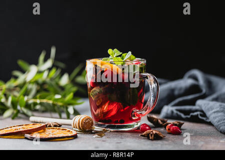 Hot spiced cranberry tea in glass cup on black background. Warming Christmas, New Year, winter or autumn drink Stock Photo
