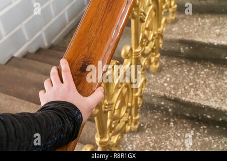 man hand holding on to the railing going up the stairs, first-person view Stock Photo
