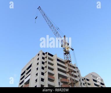 Construction - the elevating crane and unfinished brick house Stock Photo