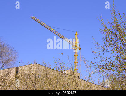 Construction - the elevating crane and unfinished brick house Stock Photo