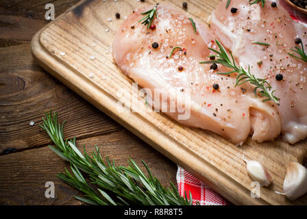 Chicken fillet with spices and rosemary on a dark wooden surface. Style rustic. Stock Photo