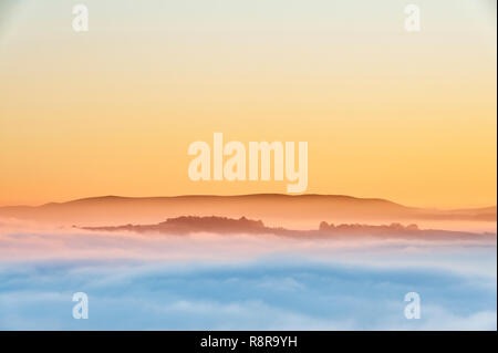 On Stonewall Hill in the Welsh borders near Knighton, UK. Evening view of Hay Bluff and the Black Mountains showing the valleys filled with thick fog Stock Photo