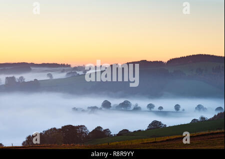 On the border between England and Wales near Knighton, Powys, UK. Evening view west from Stonewall Hill showing the valleys filled with thick fog