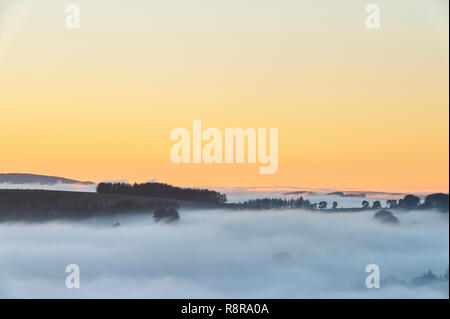 On the border between England and Wales near Knighton, Powys, UK. Evening view west from Stonewall Hill showing the valleys filled with thick fog