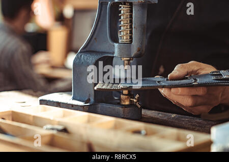 Man works in carpentry workshop. He fixes wooden handle in vice. Different tools are on workbench. Men at work. Hand work. Stock Photo