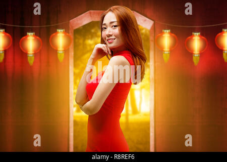 Happy chinese woman with traditional clothes posing against hanging lanterns on the background. Happy Chinese New Year Stock Photo