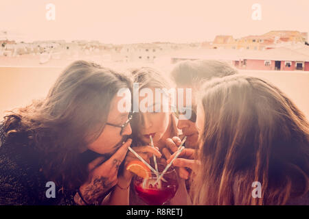 Group of friends two couples men and women celebrate and have fun together drinking from the same glass - party event time in friendship for caucasian Stock Photo