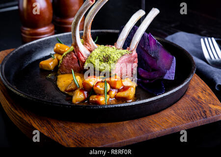 delicious restaurant dish, rack of lamb in restaurant background. Healthy exclusive food on big black platter closeup Stock Photo