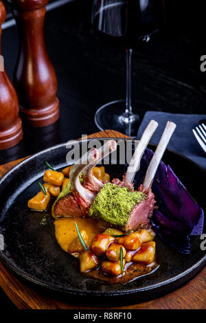 delicious restaurant dish, rack of lamb in restaurant background. Healthy exclusive food on big black platter closeup Stock Photo