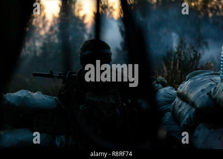 Sniper armed with large caliber, sniper rifle, shooting enemy targets on range from shelter, sitting in ambush. Back view Stock Photo