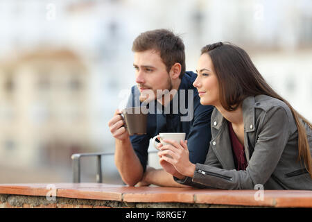 Happy couple relaxing drinking coffee in a balcony looking away on vacation Stock Photo