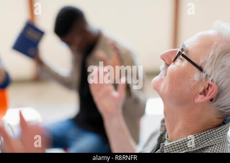 Senior man with head back praying in prayer group Stock Photo
