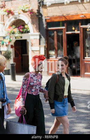 Young women friends shopping, walking on urban street Stock Photo