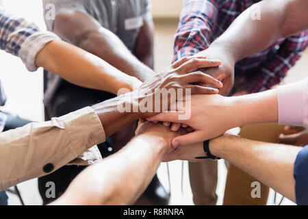 Men joining hands in huddle Stock Photo