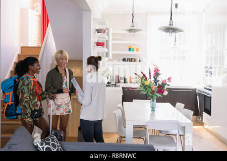 Real estate agent greeting young women friends arriving at house rental Stock Photo