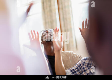 Smiling man with arms raised praying in prayer group Stock Photo