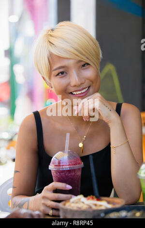 Portrait smiling, confident young woman drinking smoothie at sidewalk cafe Stock Photo