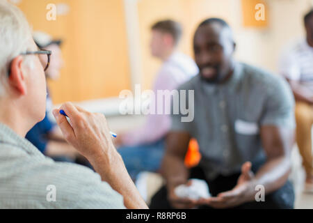 Men talking and listening in group therapy Stock Photo