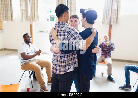Men hugging in group therapy Stock Photo