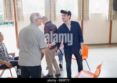 Men shaking hands in group therapy Stock Photo