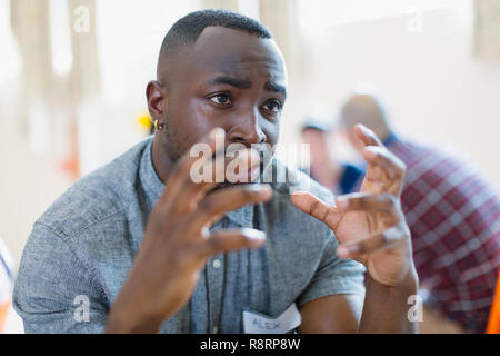 Serious young man talking, gesturing in group therapy Stock Photo