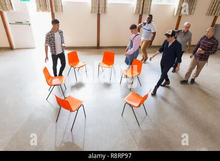 Men arriving at group therapy, sitting in circle in community center Stock Photo