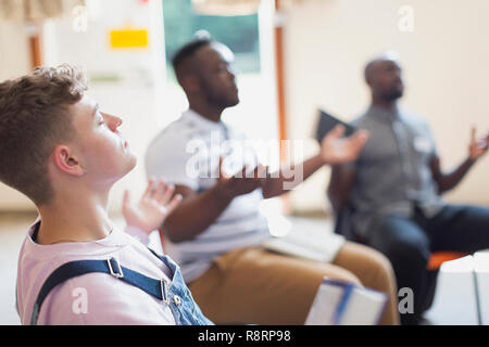 Serene man praying with arms outstretched in prayer group Stock Photo