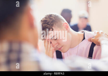 Man comforting upset teenage boy in counseling Stock Photo