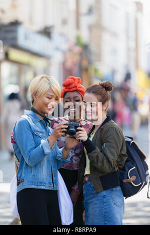 Young women friends using digital camera on urban street Stock Photo