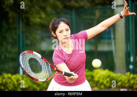 young asian woman playing tennis outdoors Stock Photo