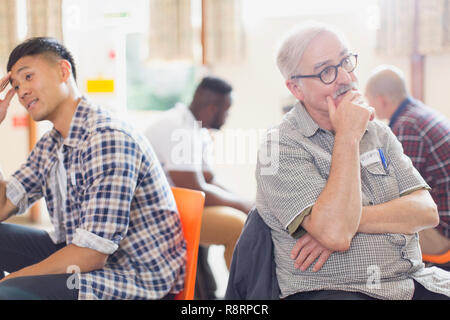 Men talking and listening in group therapy in community center Stock Photo