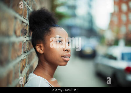 Thoughtful woman looking away on urban street Stock Photo