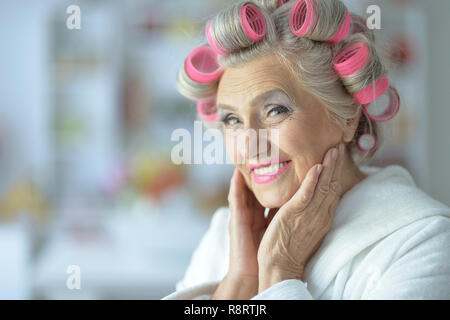 Portrait of senior woman in bathrobe with curlers Stock Photo